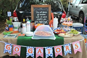 tailgate spread with assorted food and a go gators sign hanging on the front