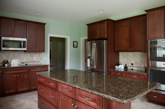 kitchen with brown cabinets, granite countertops, kitchen island, and stainless steel appliances
