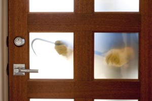 two hands holding a crowbar through frosted glass on a door