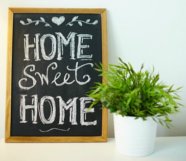 home sweet home written on a whiteboard next to a small potted plant