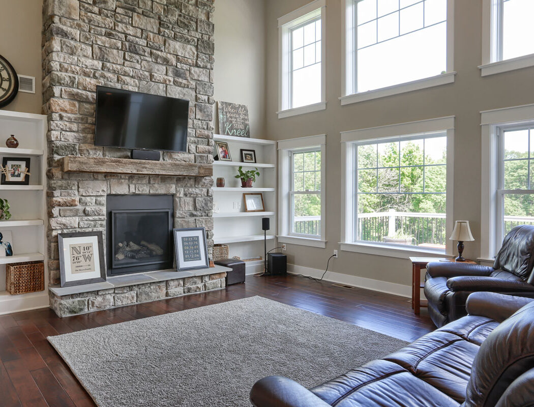 living room area with stone fireplace and a mounted TV