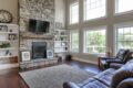 living room area with stone fireplace and a mounted TV