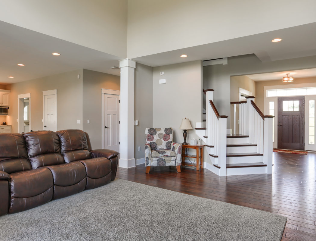 Living room area with leather couch. Staircase heading to second floor is just past the entryway on the right