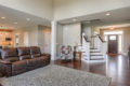 Living room area with leather couch. Staircase heading to second floor is just past the entryway on the right