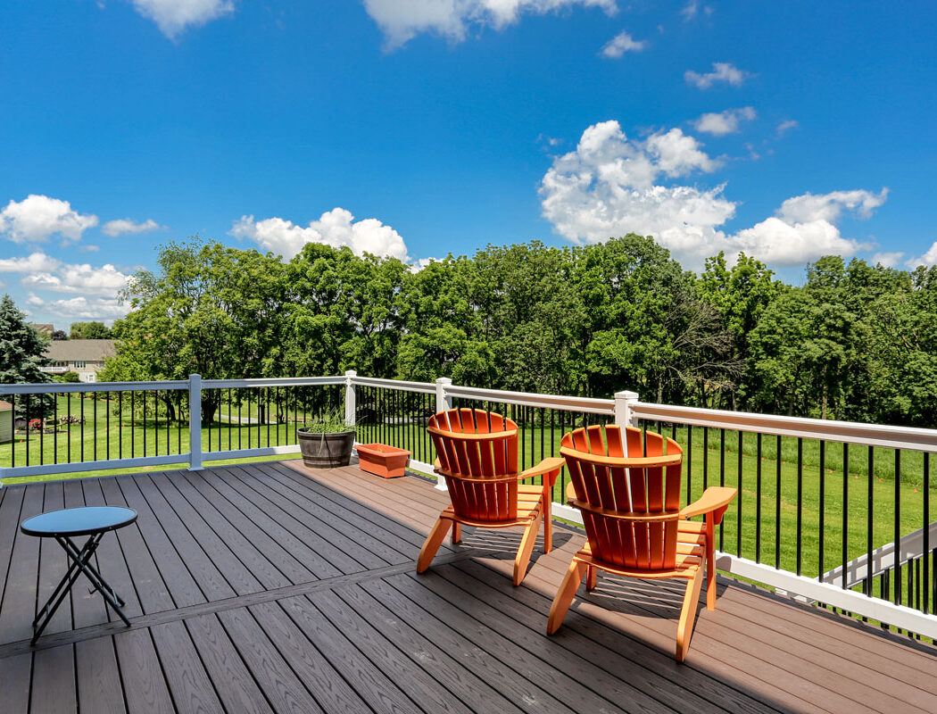 two orange chairs on a deck overlooking a lawn