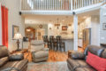 looking into the kitchen past leather furniture and the island bar with 3 wood chairs