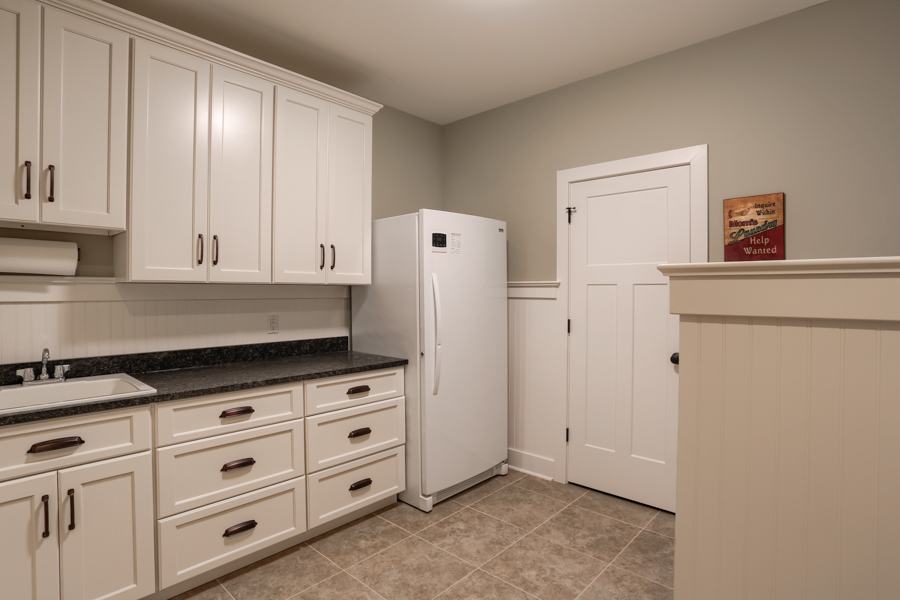 fridge and sink area with white cabinets