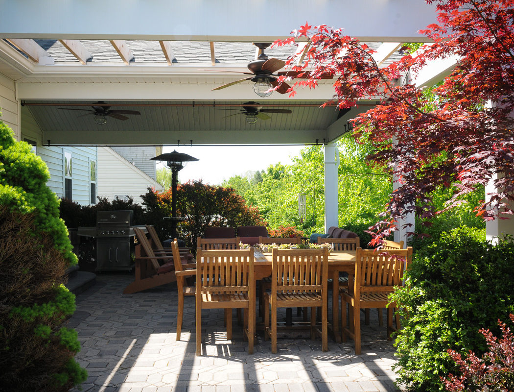 outdoor living area with various plants, patio furniture, fans and a grill