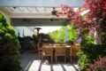 outdoor living area with various plants, patio furniture, fans and a grill