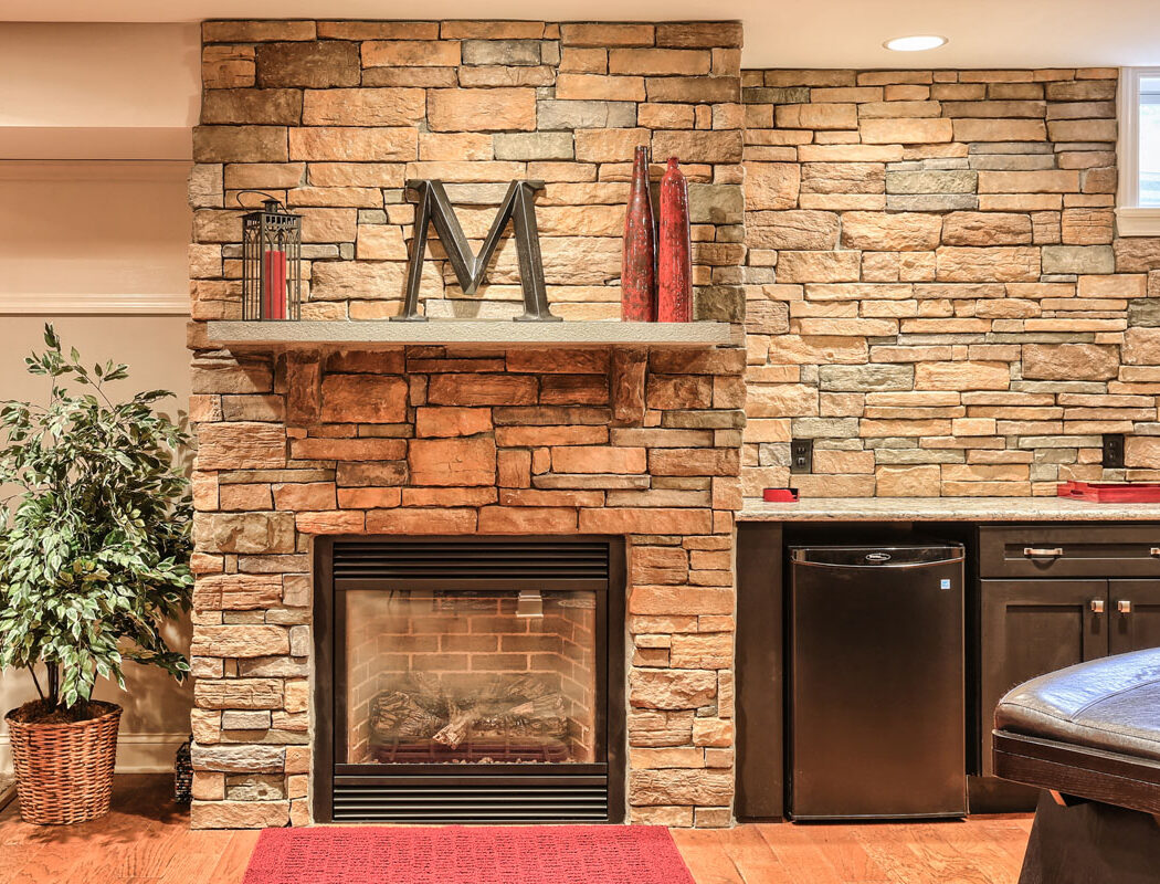 stone wall, fireplace, and refrigerator in a finished basement