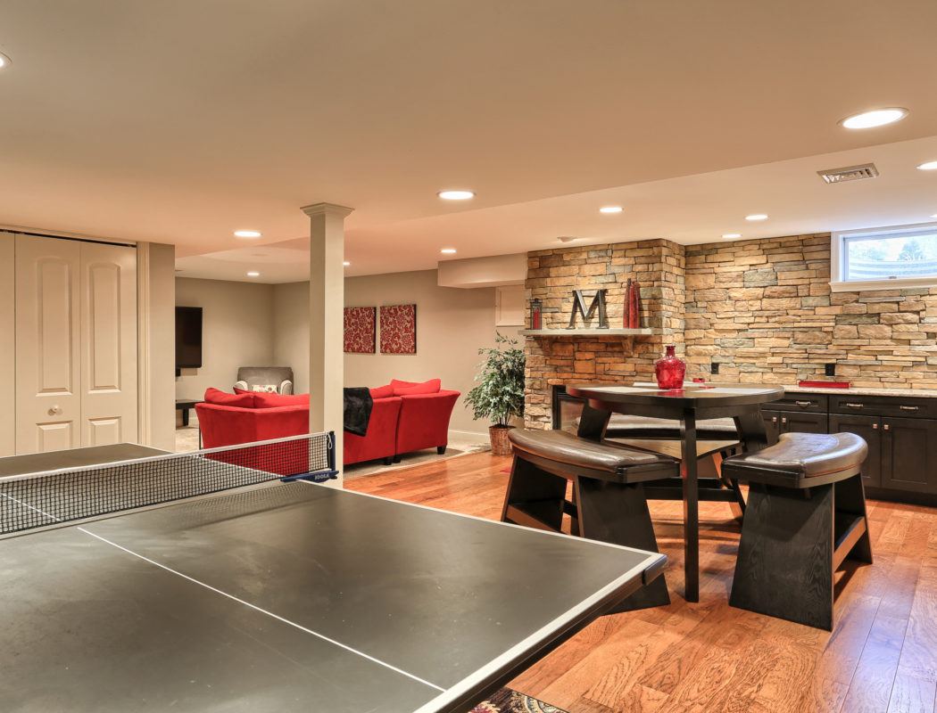 pingpong table, seating area, and a red couch inside a finished basement