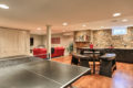 pingpong table, seating area, and a red couch inside a finished basement