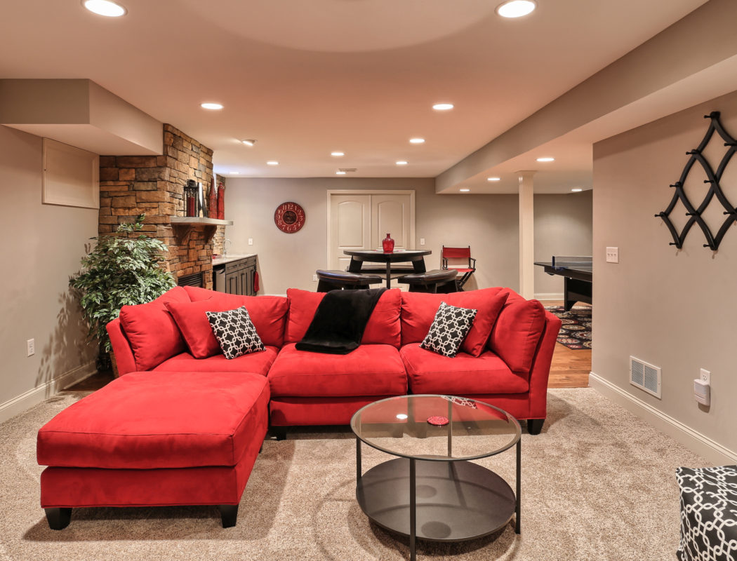 a red couch, seating area, and pingpong table in a renovated basement
