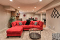 a red couch, seating area, and pingpong table in a renovated basement